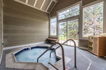 A hot tub in a room with a window overlooking a forest